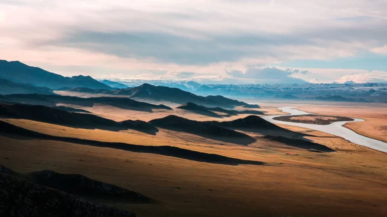 Wilderness with plains, hills, mountains, and a river flowing through the side.