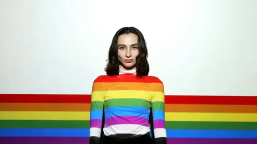 A woman standing in front of a rainbow-colored wall.