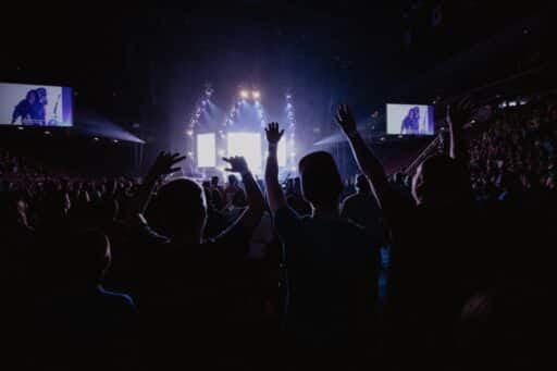 man in black suit standing on stage with people who follow the errors of hillsong church