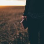 person holding book while standing on field